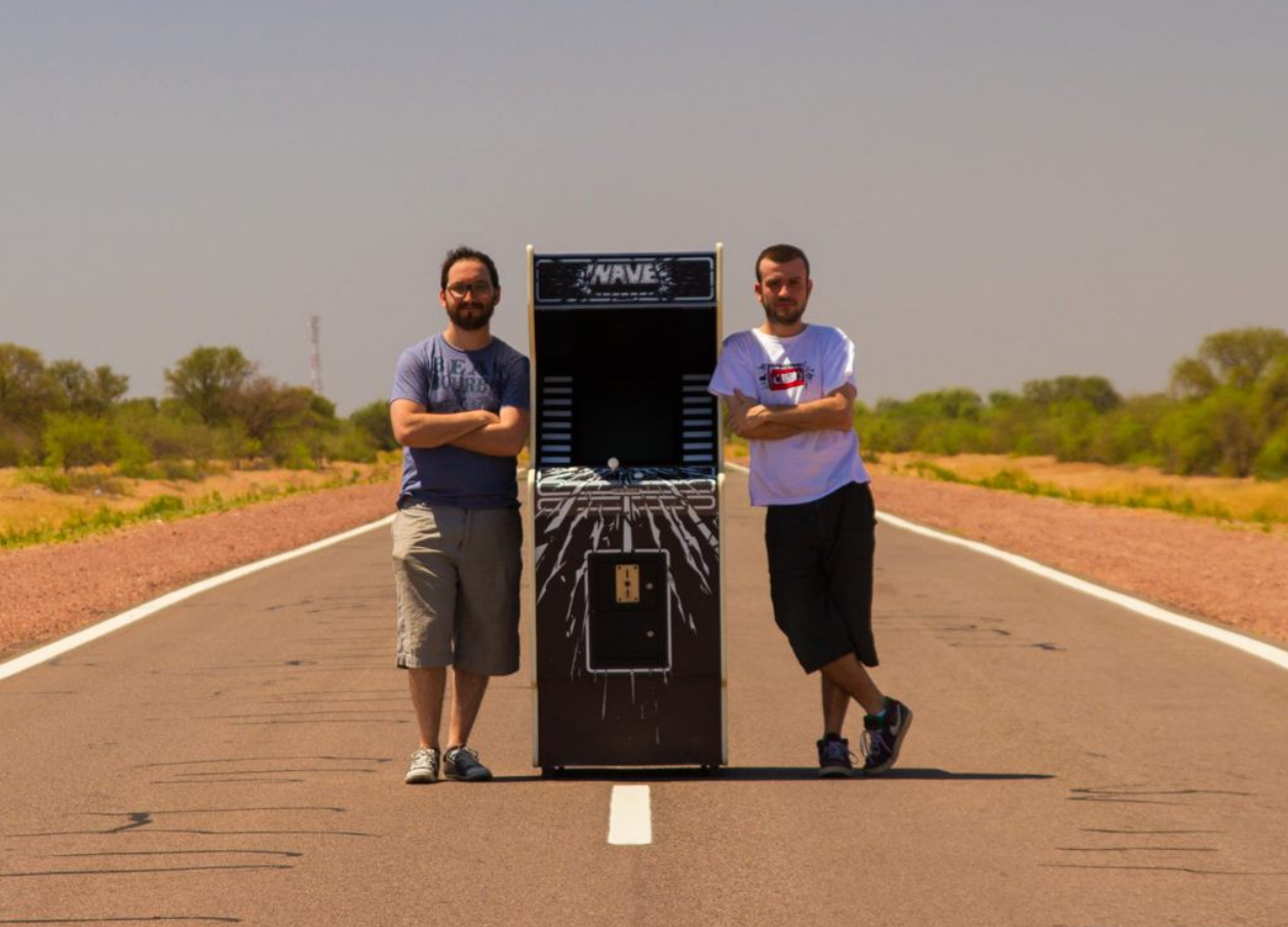 members of videgamo standing with nave arcade cabinet in middle of road