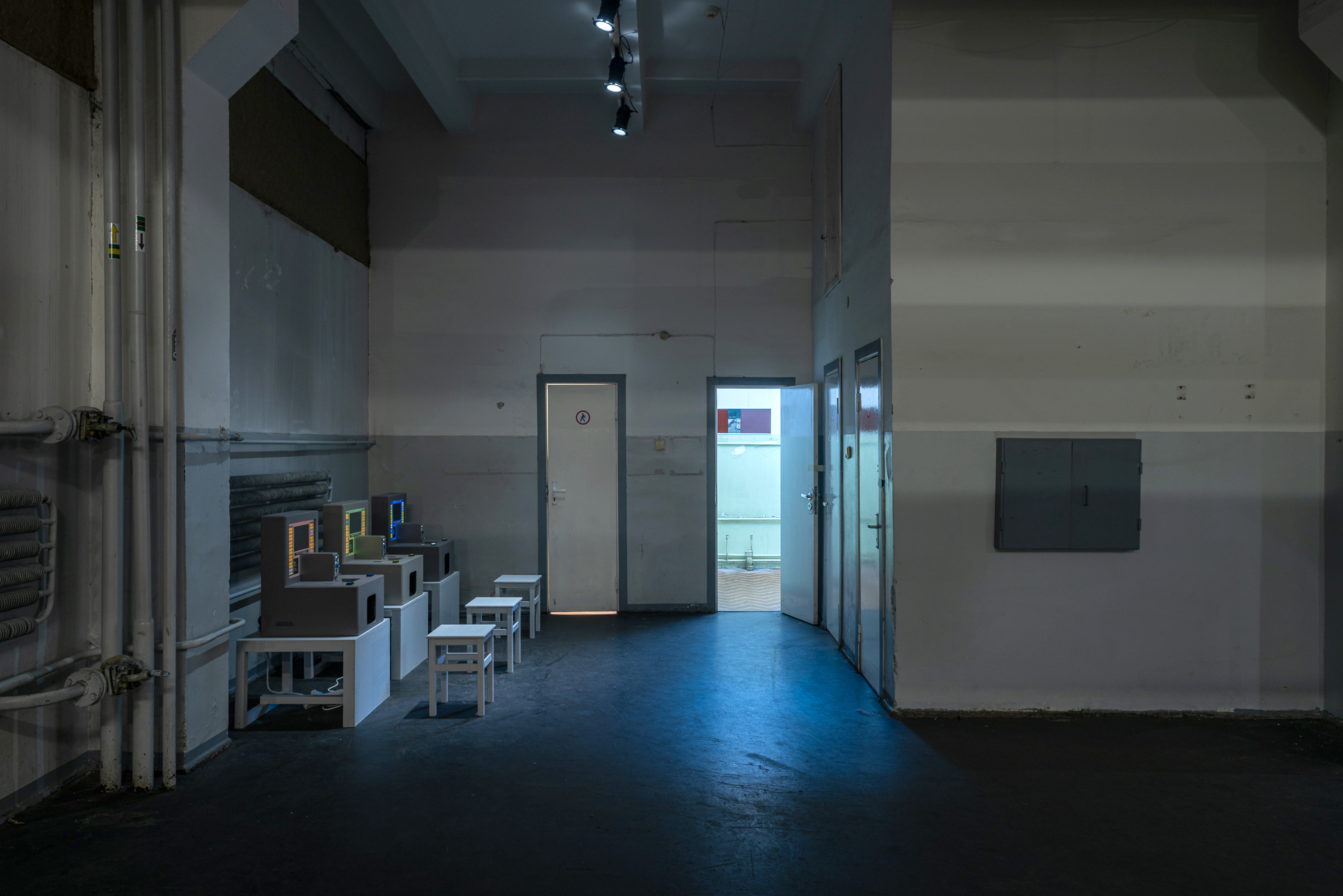 Installation shot of Untitled by Alex Mackin Dolan showing three arcade cabinets displayed in a public industrial setting 